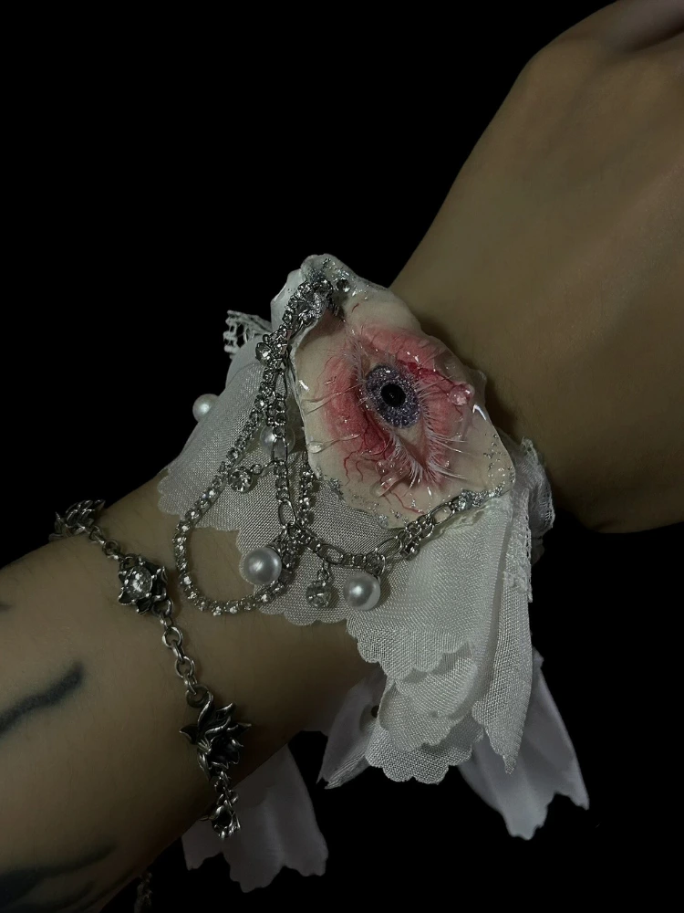 TQART detailed handcrafted seashell eyeball and chain cuff bracelet on wrist.