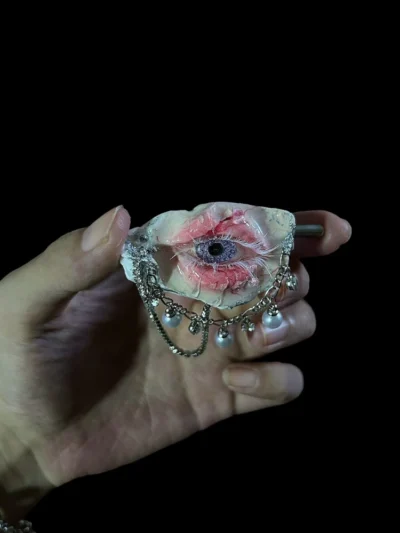 TQART artist-made realistic purple eyeball nestled in a seashell, featuring lace and pearl chain details.