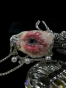 TQART realistic eyeball seashell art piece on a dark surface with other cabinet of curiosities items.