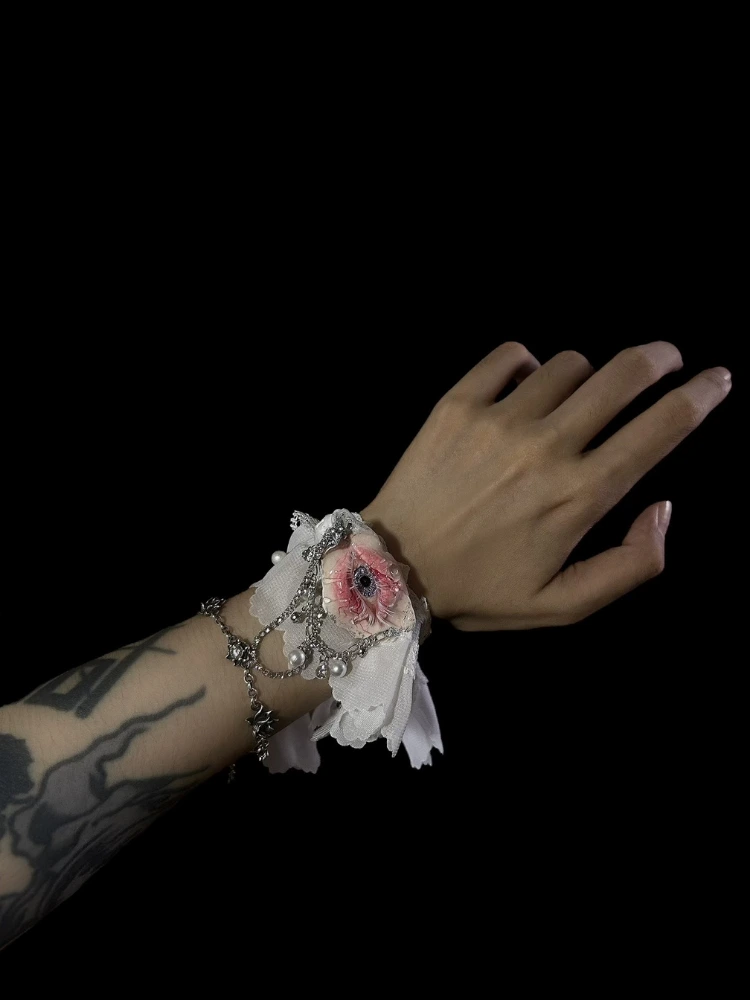 TQART realistic eyeball in seashell worn as a gothic bracelet on a tattooed wrist with lace cuff.